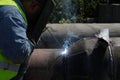 Shallow depth of field selective focus details with a professional welder welding an industrial metallic pipeline Royalty Free Stock Photo