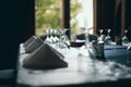 Shallow depth of field selective focus image with a restaurant table ready to receive customers. Empty glasses and tableware