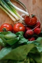 Shallow depth of field selective focus image with salad ingredients spring onions on a wooden cutter - spring onions, tomatoes,