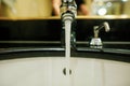 Shallow depth of field selective focus image with water running from a faucet and a soap dispenser in a hotel bathroom Royalty Free Stock Photo