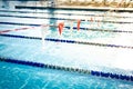 Shallow DOF string of colorful triangular backstroke flags hanging over public competitive swimming pool with pool lane divider Royalty Free Stock Photo
