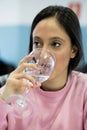 Shallow focus of a caucasian young woman drinking a glass of water against a blurred background Royalty Free Stock Photo