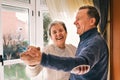 Shallow focus of a cheerful adult couple laughing and dancing in a house