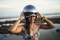 Shallow focus of a cheerful female posing with a helmet at the beach of Chiclana, Spain