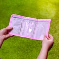 Shallow focus of child's hands holding an empty pink wallet on background of grass