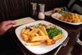 Shallow focus on chunky chips on a plate of food with pea and dover sole fish. There are two plates Royalty Free Stock Photo