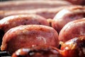 Shallow focus close up of tasty assorted delicious sausages and burgers sizzling and cooking on a barbecue griddle plate, outside Royalty Free Stock Photo