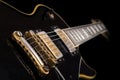 Shallow focus closeup shot of a black electric guitar in front of a black background Royalty Free Stock Photo