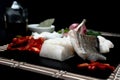 Shallow focus closeup shot of raw fish next to vegetables on a black cutting board Royalty Free Stock Photo
