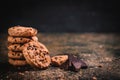 Shallow focus closeup shot of a stack of chocolate chip cookies and a piece of chocolate in crumbs Royalty Free Stock Photo