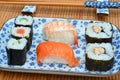 Shallow focus closeup shot of sushi rolls in plates next to chopsticks on a bamboo table cover Royalty Free Stock Photo