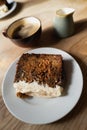 Shallow focus on the icing of a slice of carrot cake. It is on a wooden table Royalty Free Stock Photo