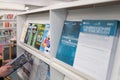 Shallow focus of magazines on a metal shelf within a municipal building.