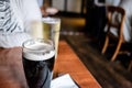 Shallow focus of a nearly full pint of a popular, Irish beer seen on a wooden table.