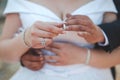 Shallow focus of a newly married couple embracing and putting rings on their fingers in a park