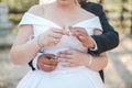 Shallow focus of a newly married couple embracing and putting rings on their fingers in a park