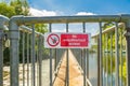 Shallow focus of a No Access Sign seen on a locked metal river crossing footbridg