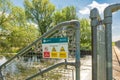 Shallow focus of a No Access Sign seen on a locked metal river crossing footbridge.