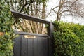 Shallow focus of an ornate, brass Private sign seen on a wooden gate leading to a private garden.