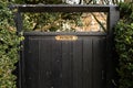 Shallow focus of an ornate, brass Private sign seen on a wooden gate leading to a private garden.