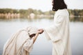 Shallow focus shot of a female grabbing the hand of Jesus Christ for healing and help