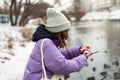 Shallow focus shot of a girl with a purple coat and a hat scrolling on her phone