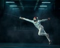 Shallow focus shot of a person fencing with a fencing mask and an epee in a dark room