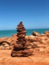 Shallow focus shot of a stack of stones column on rocky ground with blur sea in the background Royalty Free Stock Photo