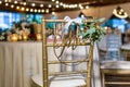 Shallow focus shot of a wedding chair for the bride decorated with white ribbon and leaves