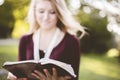 Shallow focus shot of a white female reading the Bible under the bright rays of the sun