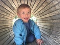 Shallow focus shot of a 2-year-old caucasian blonde baby girl in a wooden tunnel Royalty Free Stock Photo