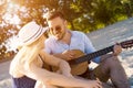 Shallow focus shot of a young Caucasian romantic couple playing the guitar in the beach Royalty Free Stock Photo