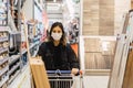 Shallow focus shot of a young female in a medical mask with a shopping trolley