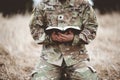 Shallow focus shot of a young soldier kneeling while holding a bible in a field