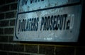 Shallow focus of a sign of Violaters Prosecuted against a brick wall
