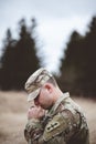 Shallow focus vertical shot of a young soldier praying in a field