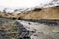 Shallow little mountain river, flows from snow-capped mountains into the gorge, on a cascade of waterfalls. Snow-covered Royalty Free Stock Photo