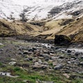 Shallow little mountain river, flows from snow-capped mountains into the gorge, on a cascade of waterfalls. Snow-covered Royalty Free Stock Photo