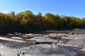 Shallow running waterfall lined with trees on a fall aftermoon