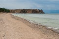 Shaman Rock on Lake Baikal in gloomy weather. Sandy shore. There is a boat near the shore.