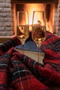 Shampagne glasses, opened book and wool scarf against cozy firepace Royalty Free Stock Photo