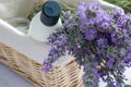 Shampoo bottle, aromatic candle and bunch of lavender flowers in wicker basket on white table background. Royalty Free Stock Photo