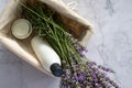 Shampoo bottle, aromatic candle and bunch of lavender flowers in wicker basket on white table background. Royalty Free Stock Photo