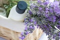 Shampoo bottle, aromatic candle and bunch of lavender flowers in wicker basket on white table background. Royalty Free Stock Photo