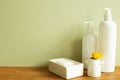 Shampoo bottle, soap, flower on wooden table. khaki green wall background Royalty Free Stock Photo