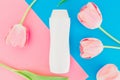 Shampoo bottle and tulips flowers on pink and blue background. Flat lay, top view Royalty Free Stock Photo