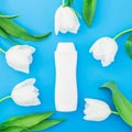 Shampoo bottle and white tulips flowers on blue background. Flat lay, top view Royalty Free Stock Photo