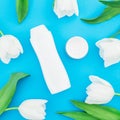 Shampoo, cream and white tulips flowers on blue background. Beauty blog. Flat lay, top view Royalty Free Stock Photo