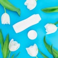 Shampoo with cream and white tulips flowers on blue background. Flat lay, top view Royalty Free Stock Photo