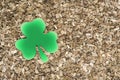 Shamrock clover made of paper on a background of wooden sawdust.